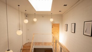 Un interior moderno con tragaluces, escalera de madera y decoración minimalista.