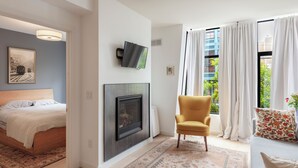 A modern living room with a fireplace, a yellow armchair, and a sofa with floral cushions. - Charming 1-bedroom condo in fabulous San Francisco with WiFi, AC fully furnished (San Francisco)