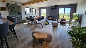 A modern living room with a large sofa, dining area, and a fireplace.