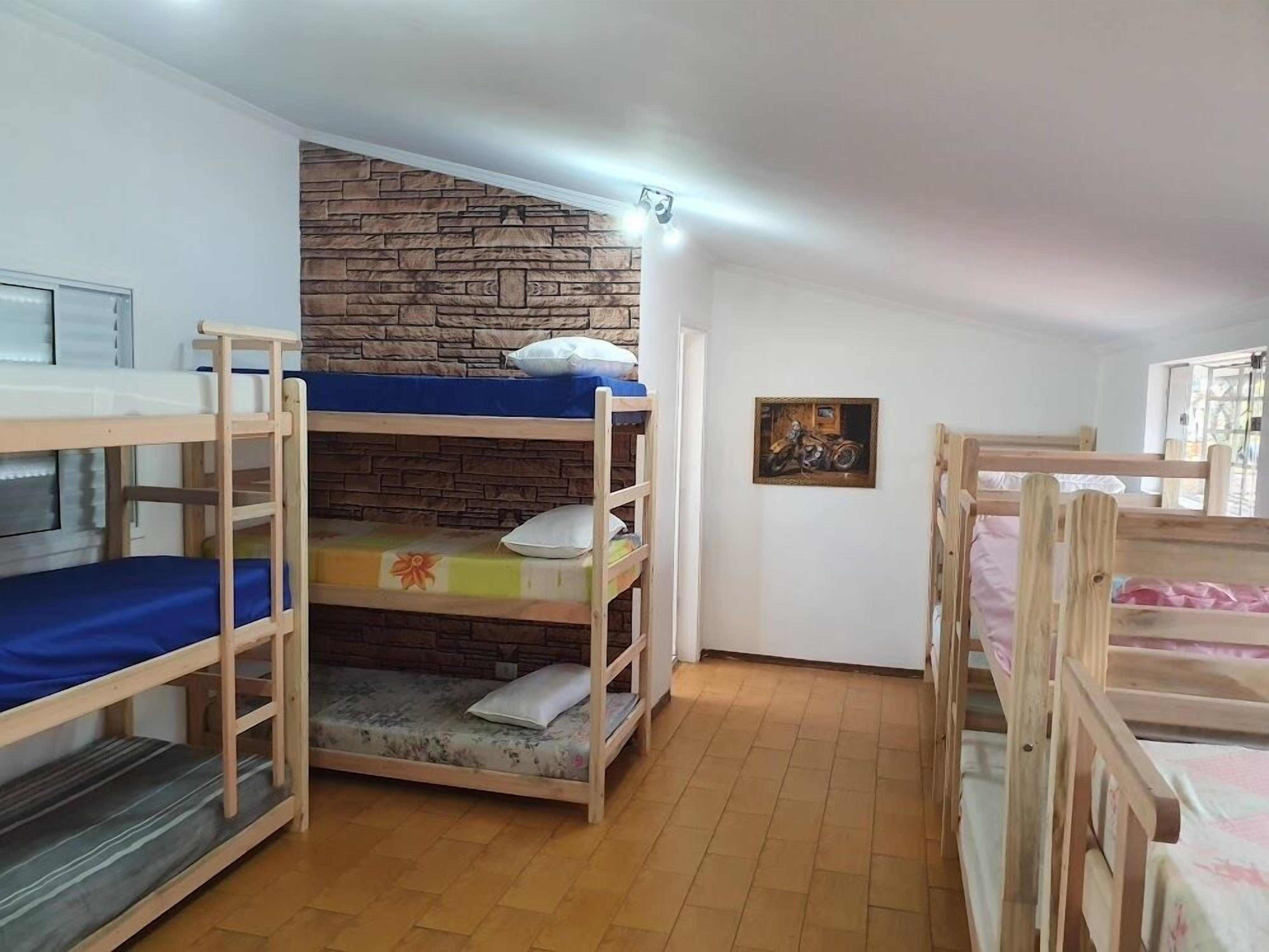 Un dormitorio con literas, pared de piedra, un cuadro enmarcado y una ventana.