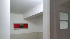 A small, narrow room with a single bed, a wall-mounted shelf, and a window with blinds. - WR7 Hostel (Sao Bernardo do Campo)