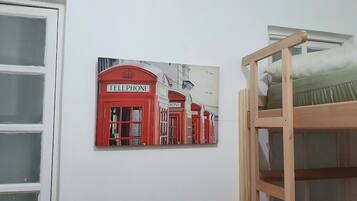 A bunk bed with a green mattress, a white wall, and a red telephone booth artwork.