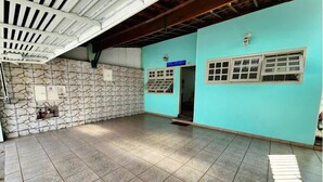 A spacious indoor area with a stone wall and tiled floor, featuring a blue wall and a window with a grid pattern. - WR7 Hostel (Sao Bernardo do Campo)