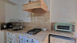 Een kleine keuken met een gasfornuis, een broodrooster en een koffiezetapparaat.