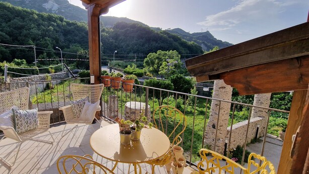 Een balkon met rieten meubels, een ronde tafel en planten in potten.