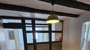 A room with exposed brick walls, wooden flooring, and a hanging light fixture. - Green apartment on the estate (Nordstemmen)