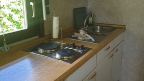 Een kleine keuken met een houten aanrecht, een spoelbak en een fornuis.