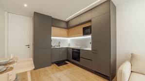 Een moderne keuken met grijze kastjes, een houten aanrechtblad en een ingebouwde magnetron.