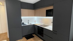 Een moderne keuken met donkere kastjes, een wit aanrechtblad en een houten vloer.
