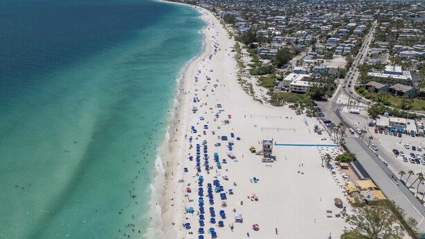 An aerial view of a beach with numerous umbrellas and beachgoers. - Gulf View Getaway |  Sand & Sunset Views Daily! (Holmes Beach)