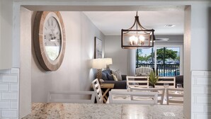 A modern living room with a large clock, a dining area with a marble countertop, and a view of the outdoors through large windows. - Gulf View Getaway |  Sand & Sunset Views Daily! (Holmes Beach)