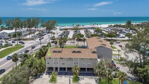 A beachfront hotel with multiple parking lots, a road leading to the beach, and a view of the ocean. - Gulf View Getaway |  Sand & Sunset Views Daily! (Holmes Beach)