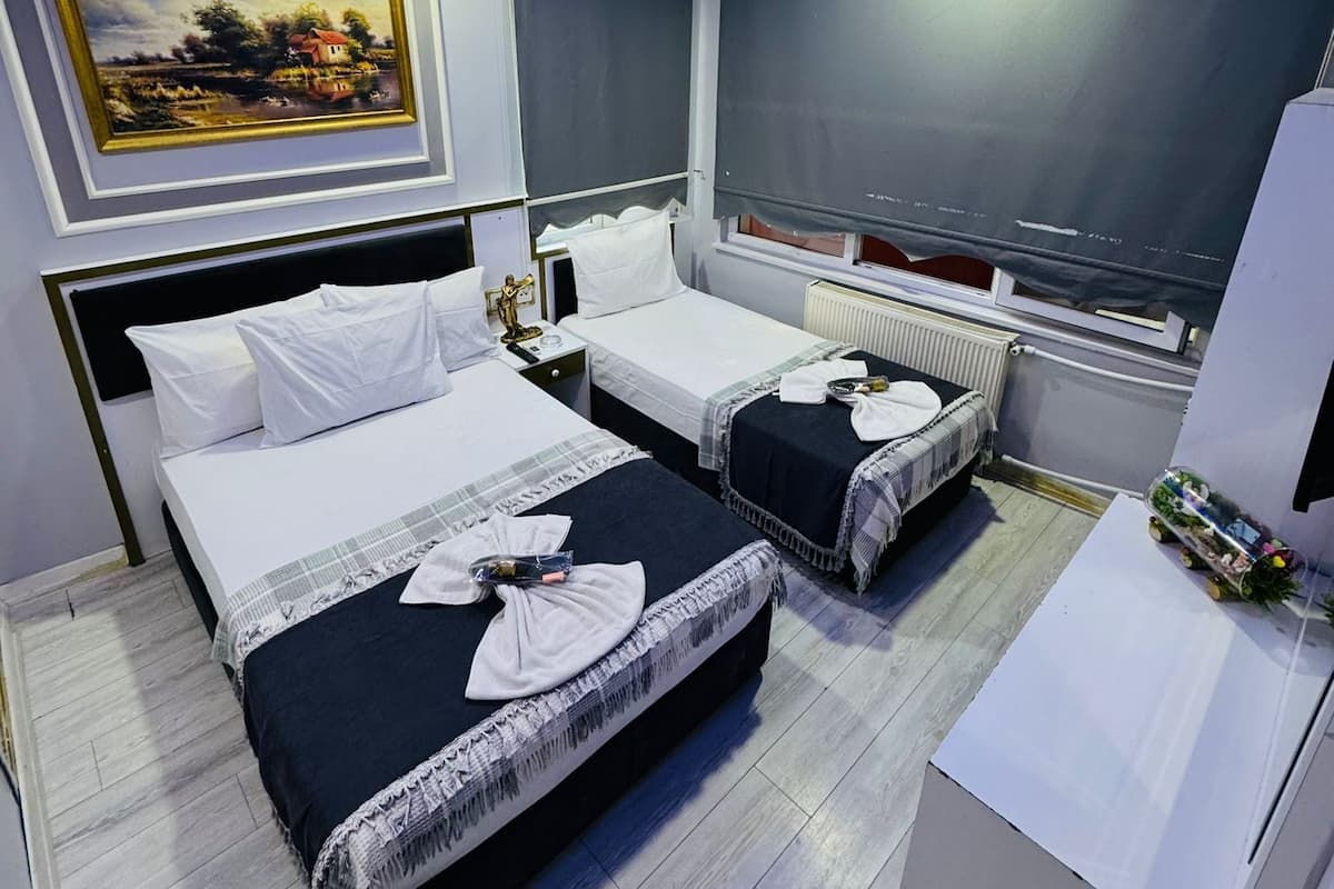 A hotel room with two beds, a painting on the wall, and a window with a view.