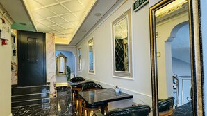 A hotel lobby with a marble floor, a long table with chairs, a large mirror, and a ceiling with a geometric pattern. - BİLAL HOTEL (Istanbul)