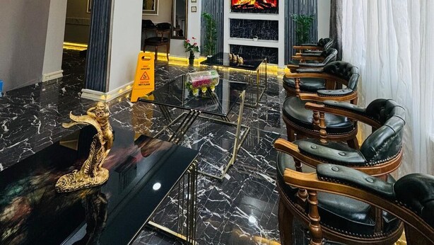 A spacious lobby with a marble floor, leather seating, a fireplace, and a television. - BİLAL HOTEL (Istanbul)