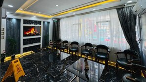 A hotel room with a black marble floor, a fireplace, a large window with sheer curtains, and several black upholstered chairs. - BİLAL HOTEL (Istanbul)