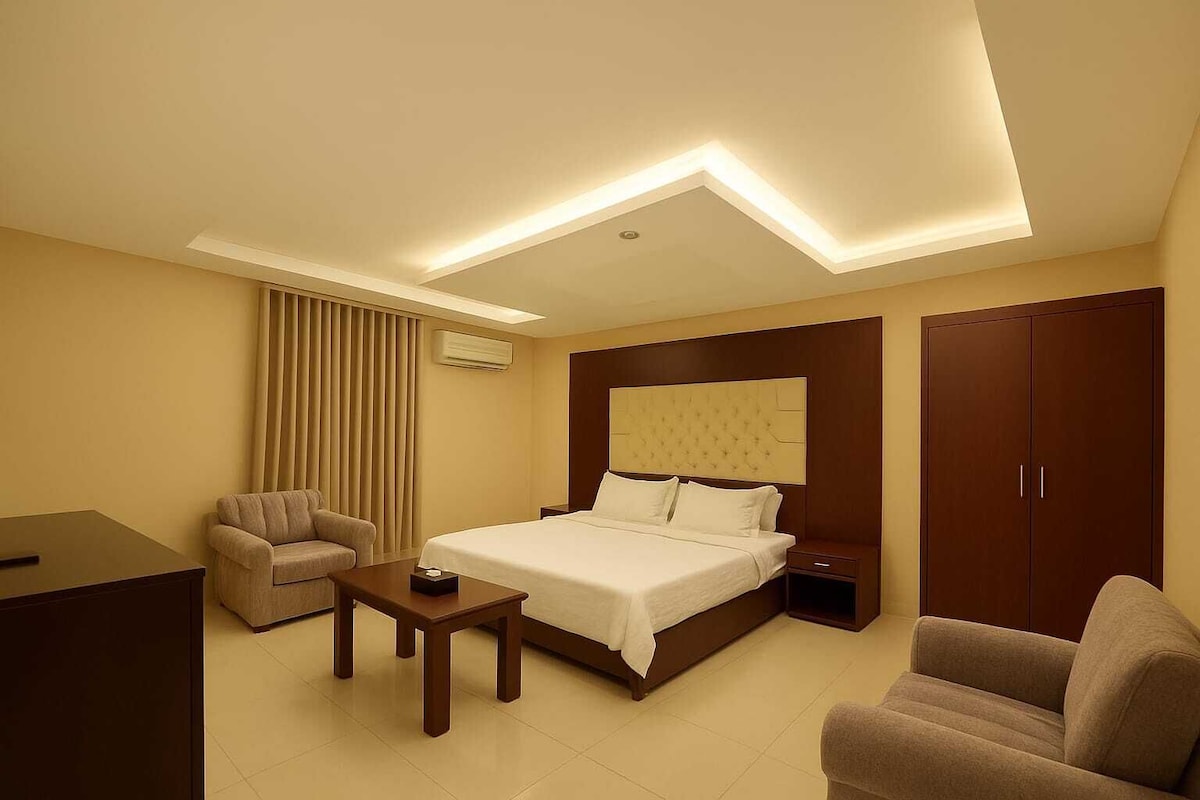 Une chambre d’hôtel comprenant un lit, un bureau, une chaise, une table de chevet et une armoire.