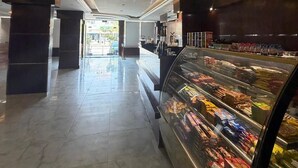 A clean, modern interior with a marble floor, a glass display case with snacks, and a view of the outside. - Rama Dubai Hotel Suites 1 (Riyadh)