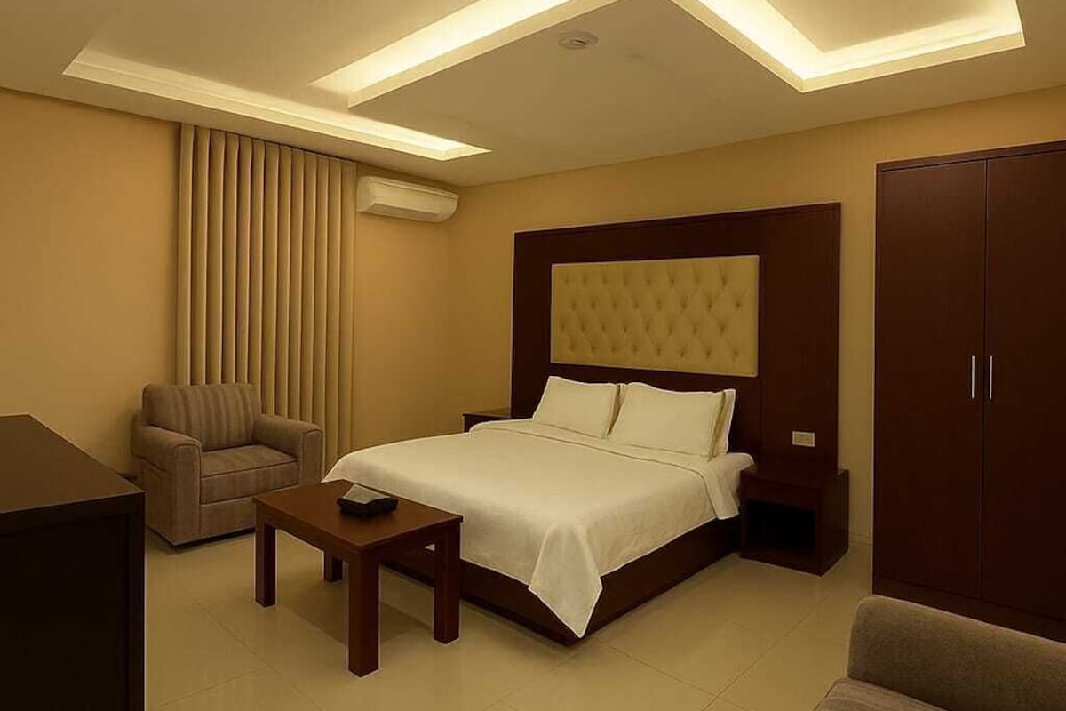 Une chambre d’hôtel moderne, dotée d’un grand lit, d’un canapé, d’un bureau et d’une armoire.