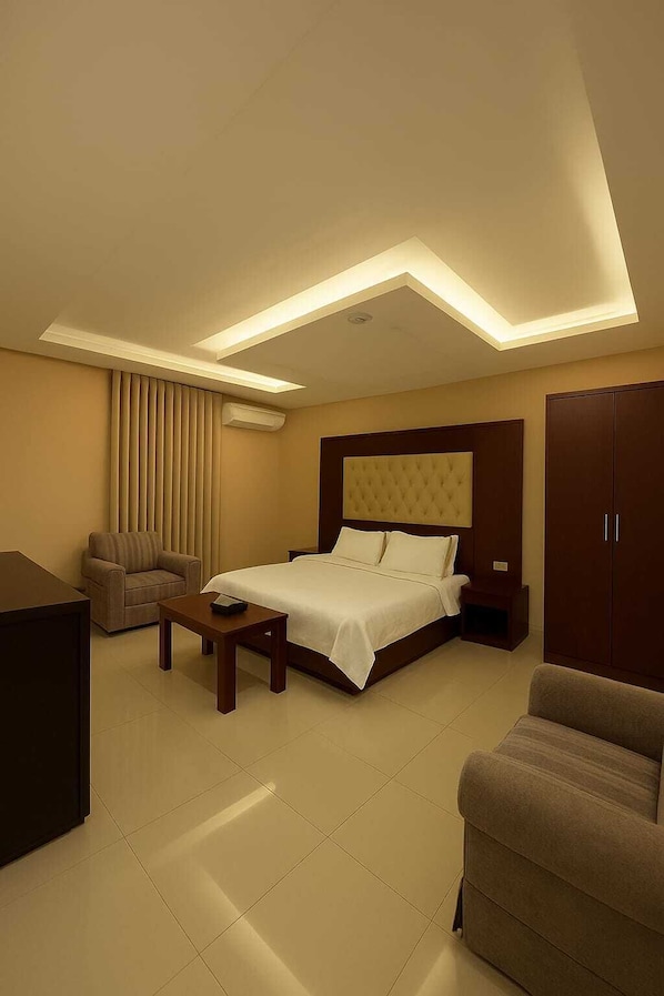 Une chambre d’hôtel moderne, dotée d’un grand lit, d’un canapé, d’un bureau et d’une armoire.