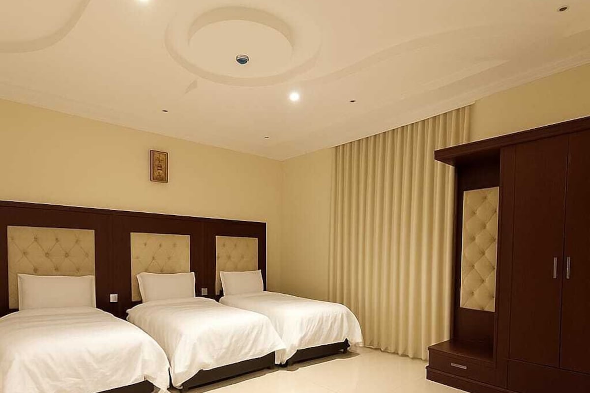 Une chambre d’hôtel avec deux lits, une grande armoire et un plafond doté d’un éclairage encastré.