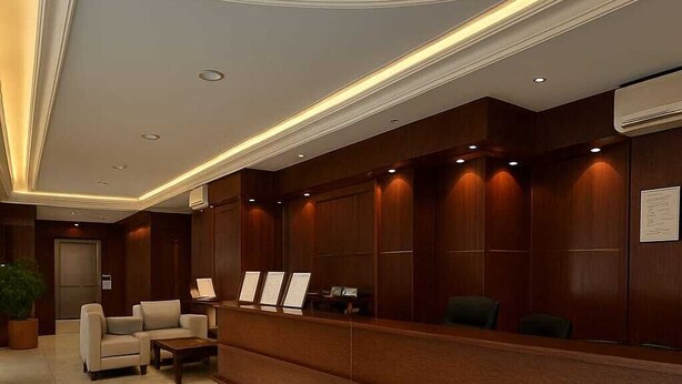 A reception area with a marble floor, wooden reception desk, and seating area with chairs. - Rama Dubai Serviced Apartments (Riyadh)
