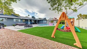 Un jardin avec une balançoire, une piscine et un espace patio.