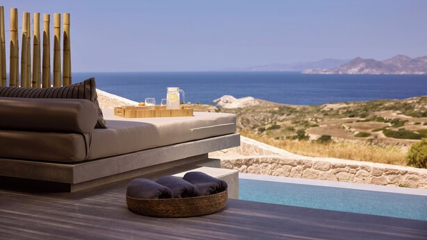 A modern outdoor seating area with a view of the sea and mountains. - Kemelia Suites (Milos)