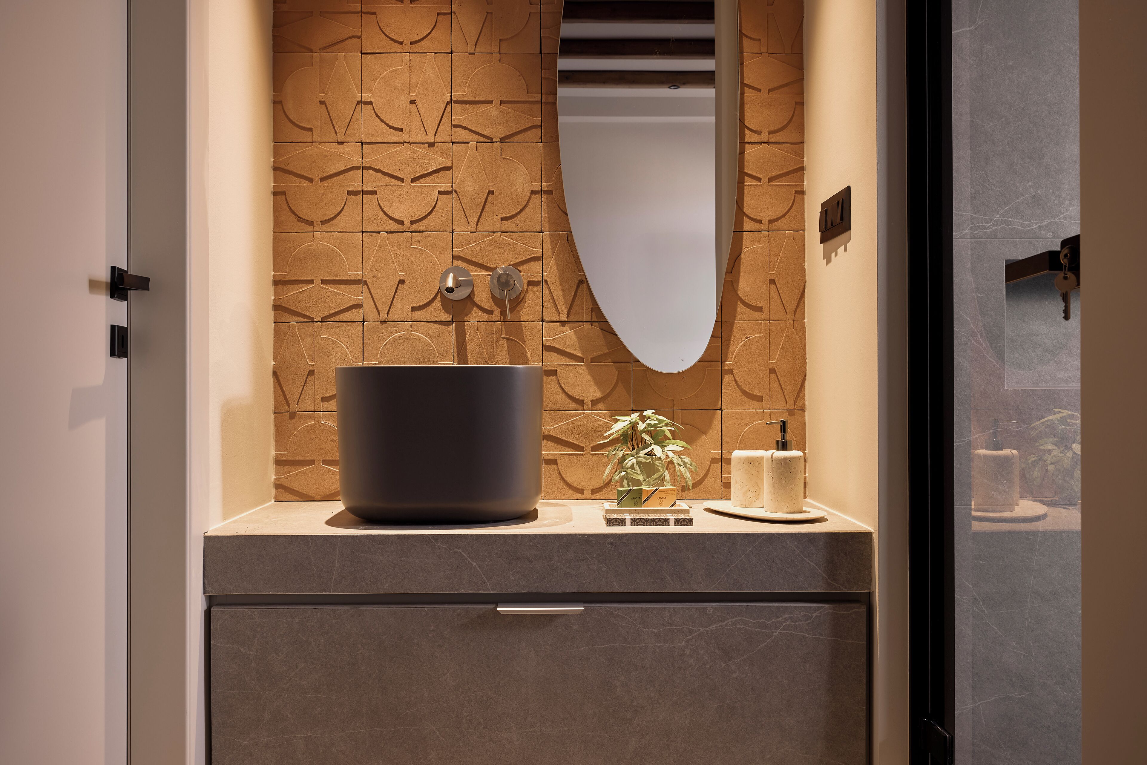 A bathroom with a large, modern sink, a mirror, and a decorative wall panel.