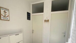 Un pasillo con armarios blancos, un cartel enmarcado y dos puertas con felpudos que dicen 'HOME'.