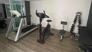 Ein modernes Fitnessstudio mit Laufband, Ergometer, Kurzhanteln und einer Trainingsbank.