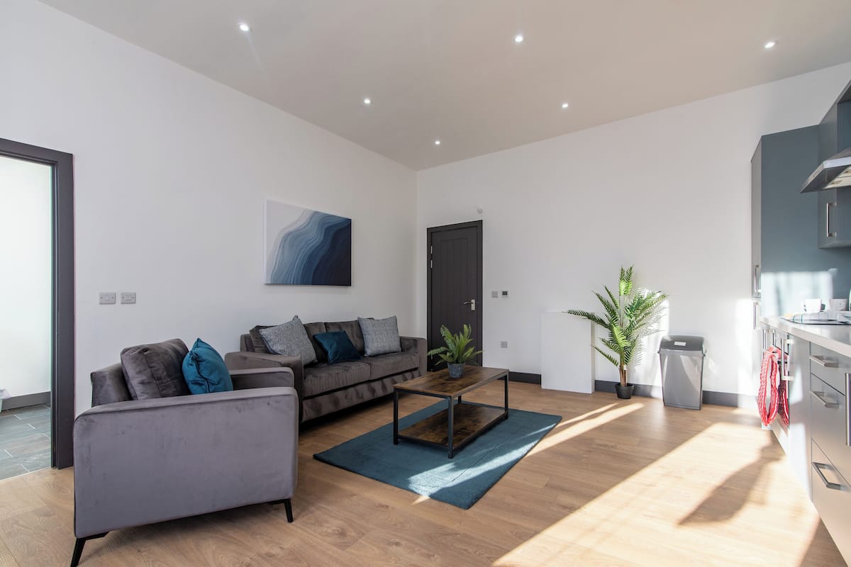 Un salon moderne avec un canapé gris, une table basse et une plante en pot.