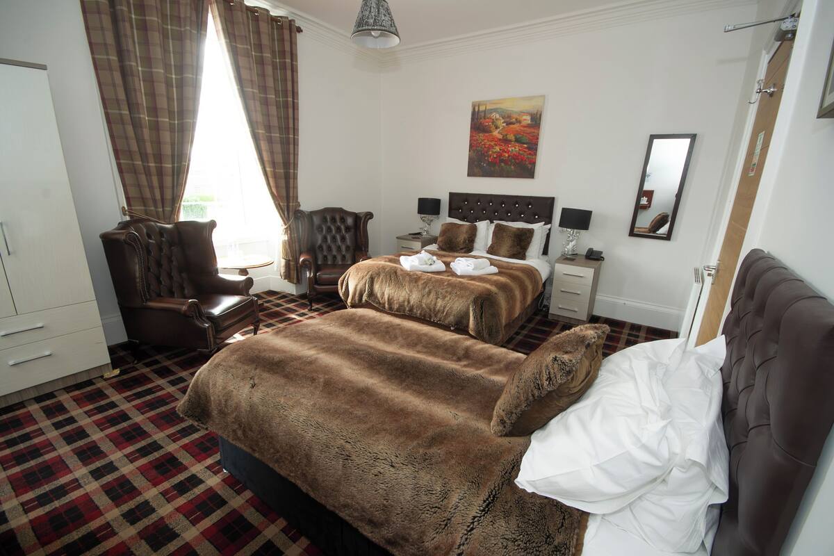 A hotel room with a large bed, a chair, a desk, and a painting on the wall.