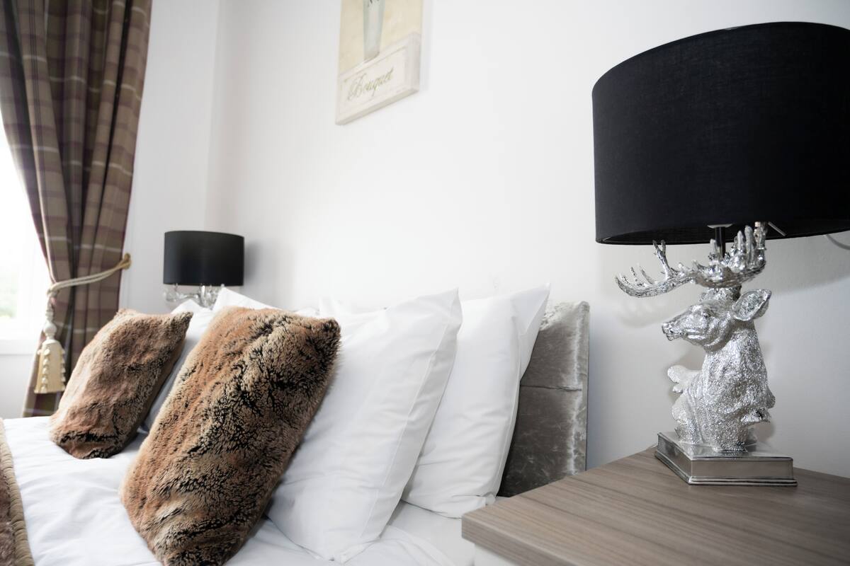 A hotel room with a bed, a lamp, and a decorative silver statue.