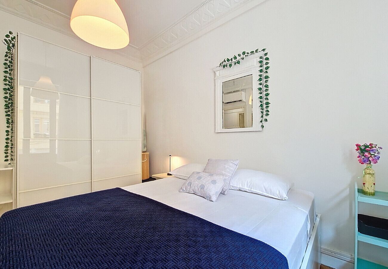 Une chambre à coucher comprenant un lit, une table de chevet, une lampe et un miroir orné de motifs de feuilles.