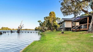 A lakeside property with a grassy lawn, a dock, and a building with outdoor seating. - Black Shack - 13 Paisley Island (Paisley)