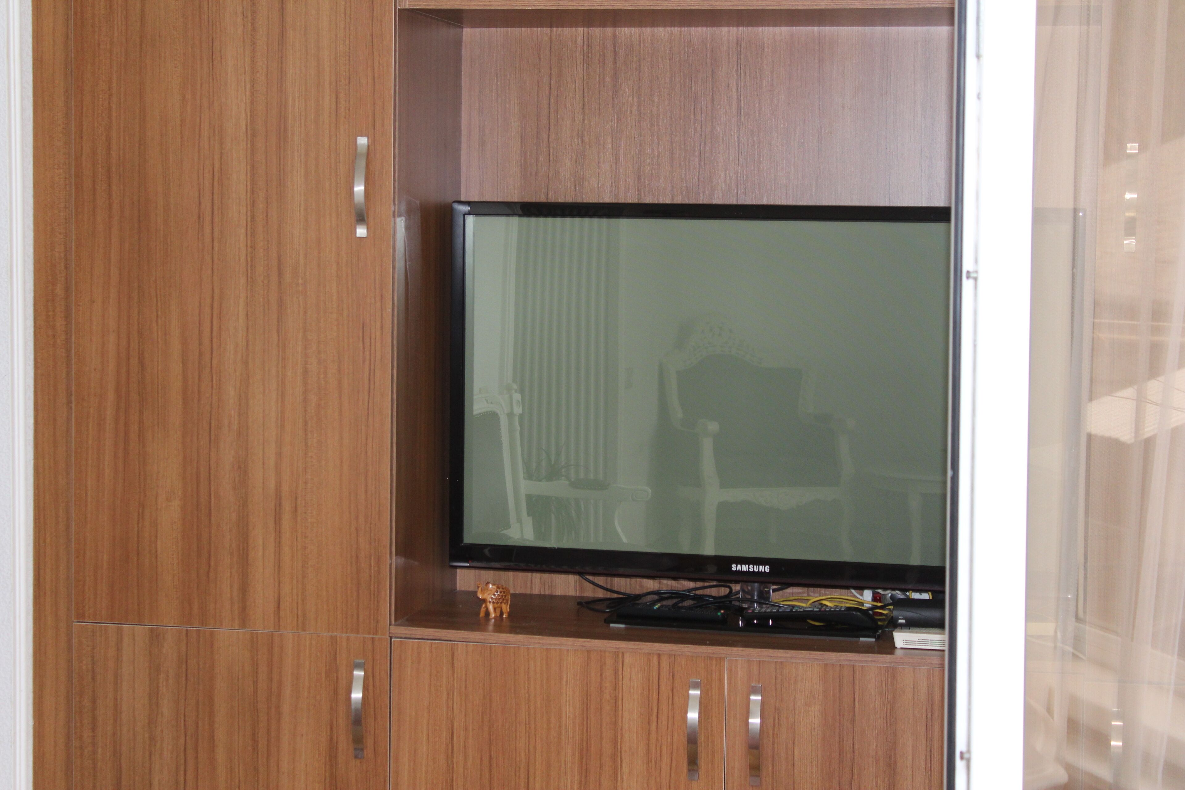 Un mueble de madera con un televisor de pantalla plana, una figurita y un decodificador.