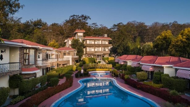 A resort with a swimming pool, multiple buildings, and well-maintained gardens. - Country Inn Tarika Riverside Resort Jim Corbett (Ramnagar)
