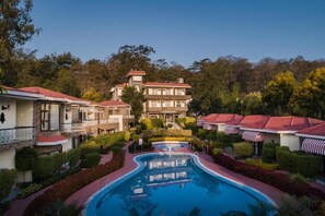 A resort with a swimming pool, multiple buildings, and well-maintained gardens. - Country Inn Tarika Riverside Resort Jim Corbett (Ramnagar)