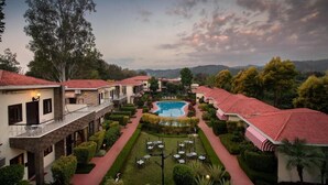A hotel with a central pool, multiple guest rooms, and a well-maintained garden. - Country Inn Tarika Riverside Resort Jim Corbett (Ramnagar)