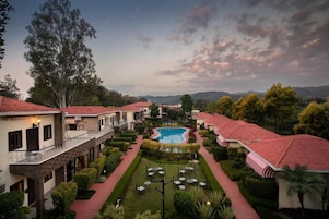 Un hotel con piscina central, varias habitaciones y un jardín bien cuidado.