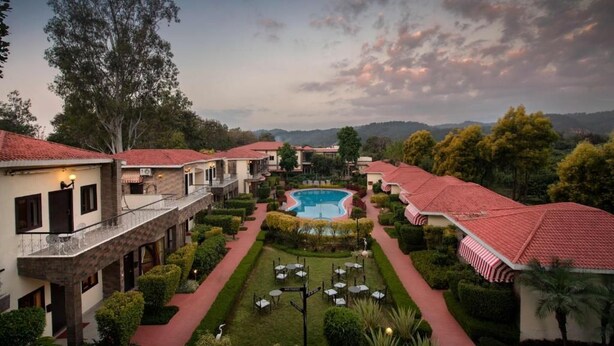 A hotel with a central pool, multiple guest rooms, and a well-maintained garden. - Country Inn Tarika Riverside Resort Jim Corbett (Ramnagar)
