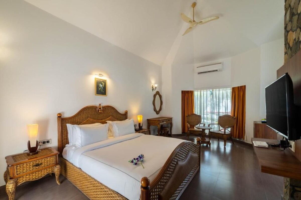 A hotel room with a large bed, a television, a desk, and a dining area.