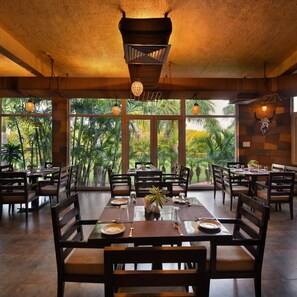 A restaurant with large windows, wooden furniture, and hanging lights. - Country Inn Tarika Riverside Resort Jim Corbett (Ramnagar)