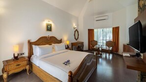A hotel room with a large bed, a television, a desk, and a dining area. - Country Inn Tarika Riverside Resort Jim Corbett (Ramnagar)