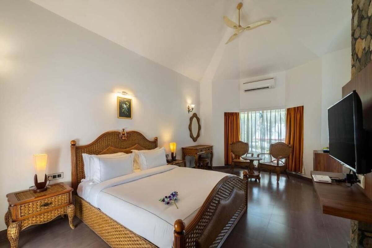 A hotel room with a large bed, a television, a desk, and a dining area.