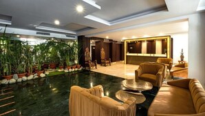 A spacious lobby with a marble floor, plush seating, and a variety of plants. - Country Inn Tarika Riverside Resort Jim Corbett (Ramnagar)