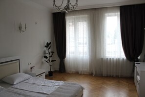 Un dormitorio con cama, mesita de noche, lámpara y ventana con cortinas.
