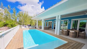 A poolside area with a wooden deck, outdoor furniture, and a covered seating area.