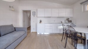 Una cucina moderna con mobili bianchi, un tavolo da pranzo e sedie trasparenti.